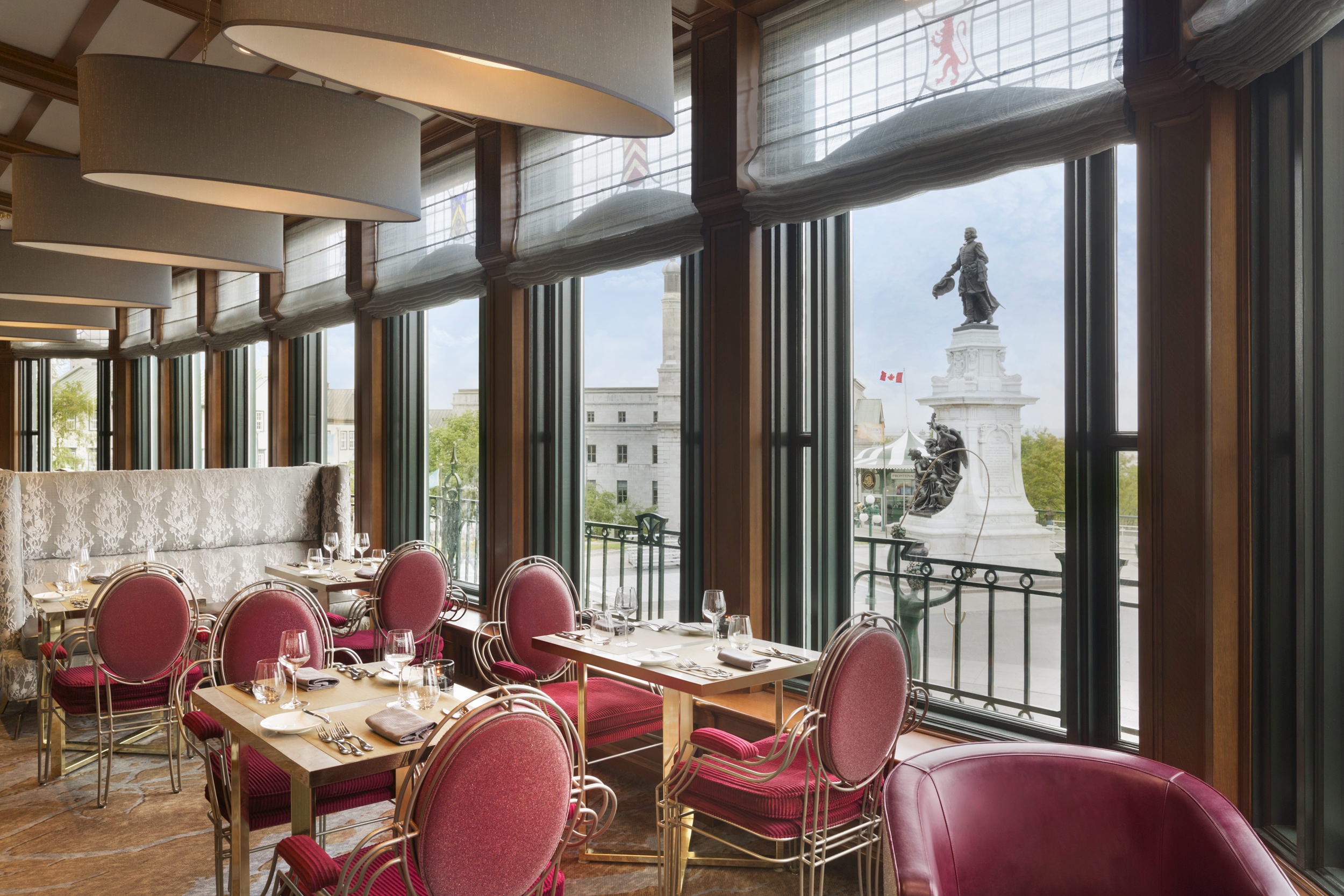 dining tables with deep pink chairs and view of statue outside