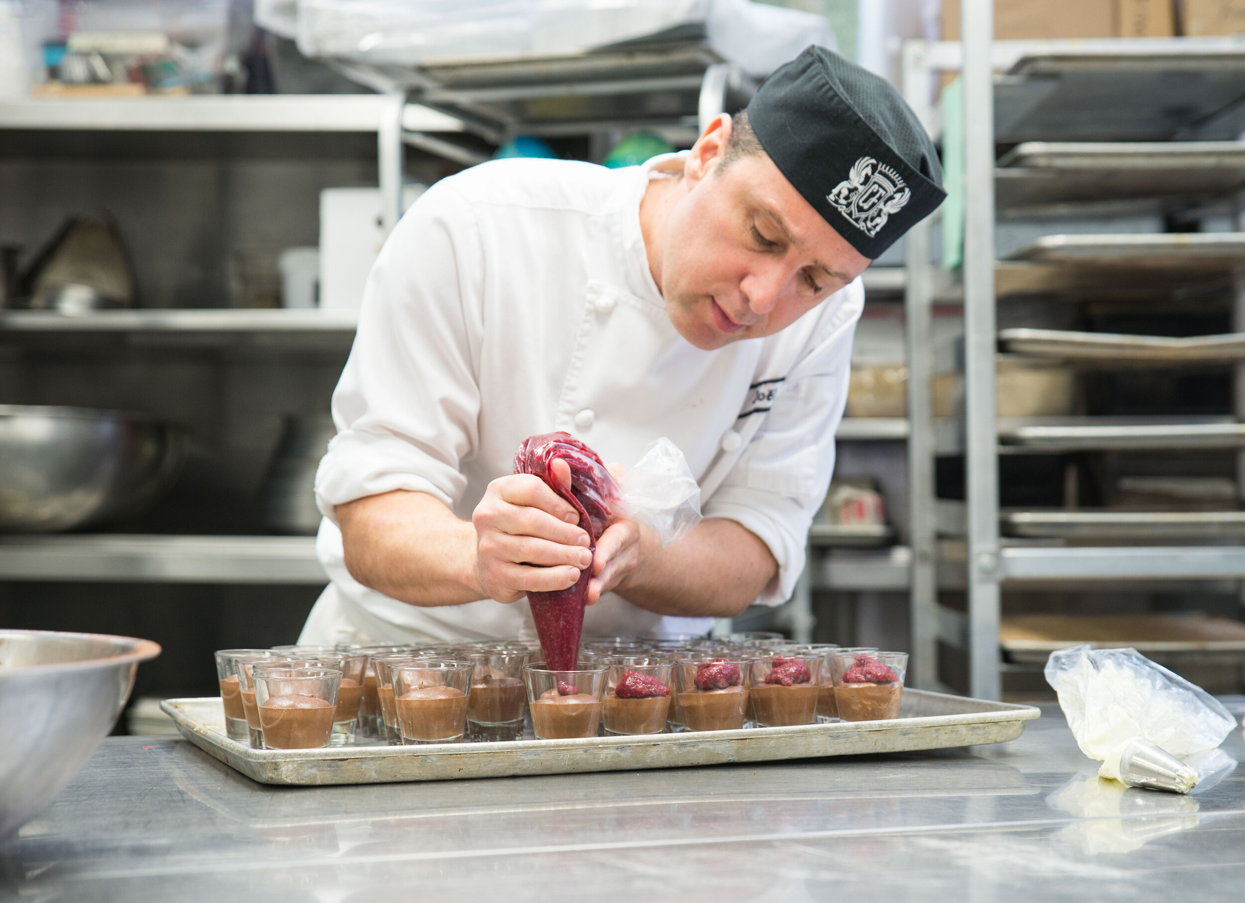 chef joel adding frosting to small dessert dish