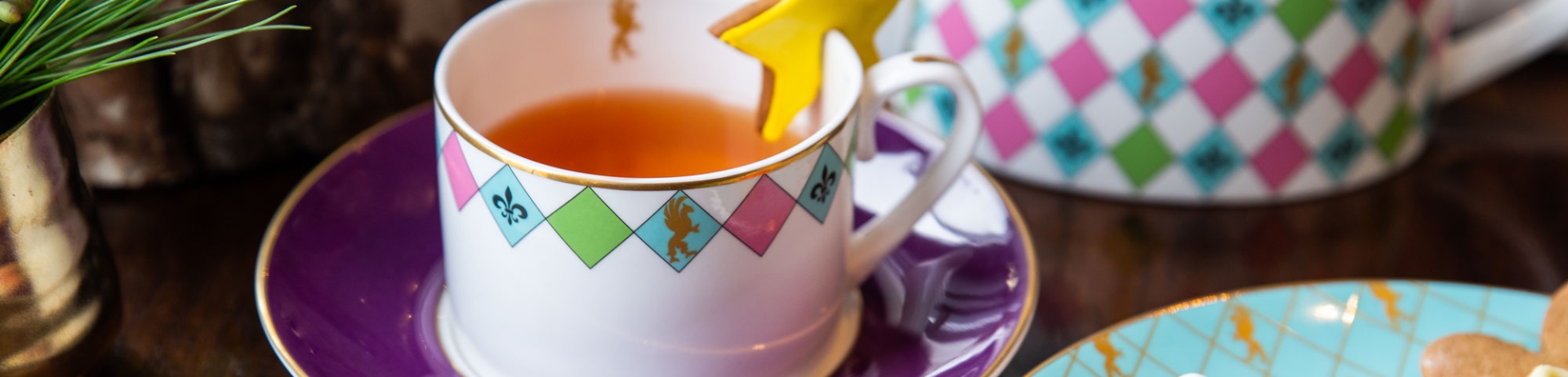 Tea cup garnished with gingerbread star beside a plate of holiday desserts