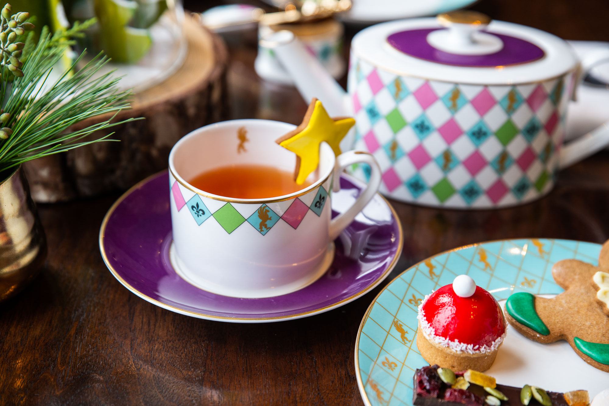 Tea cup garnished with gingerbread star beside a plate of holiday desserts