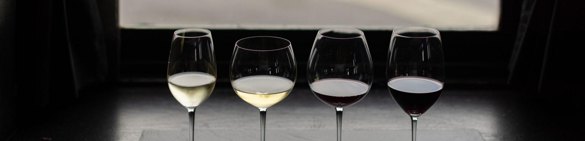 Array of wine glasses on a table in front of a window