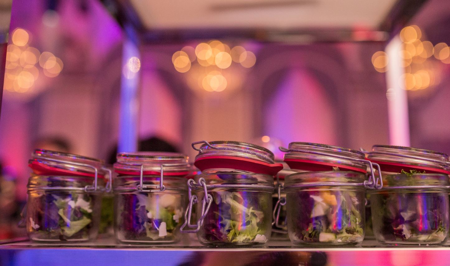 Row of salads in small mason jars on a counter top