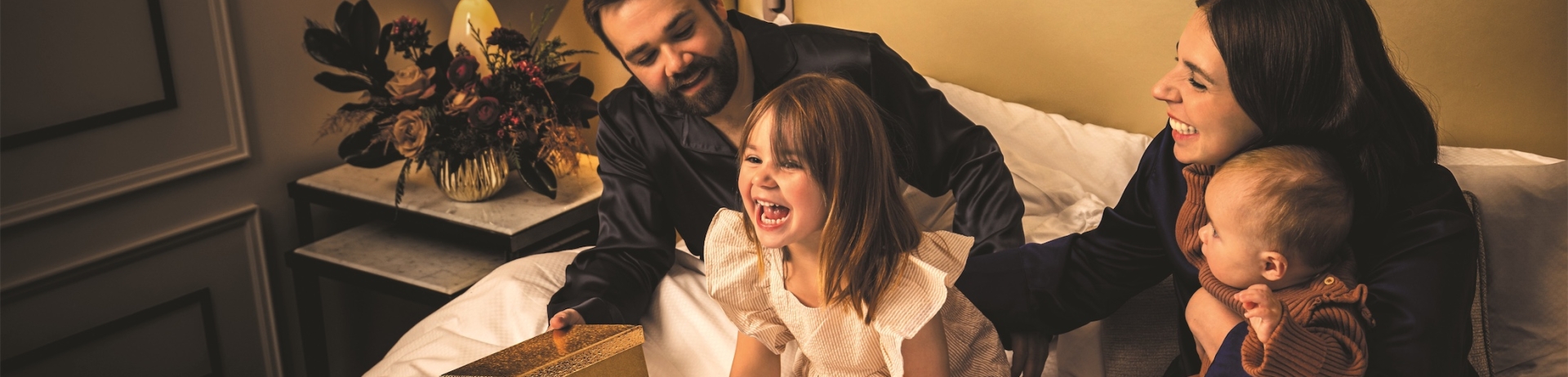 A family on a hotel bed laughing with presents