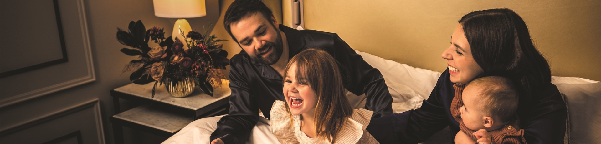 A family on a hotel bed laughing with presents