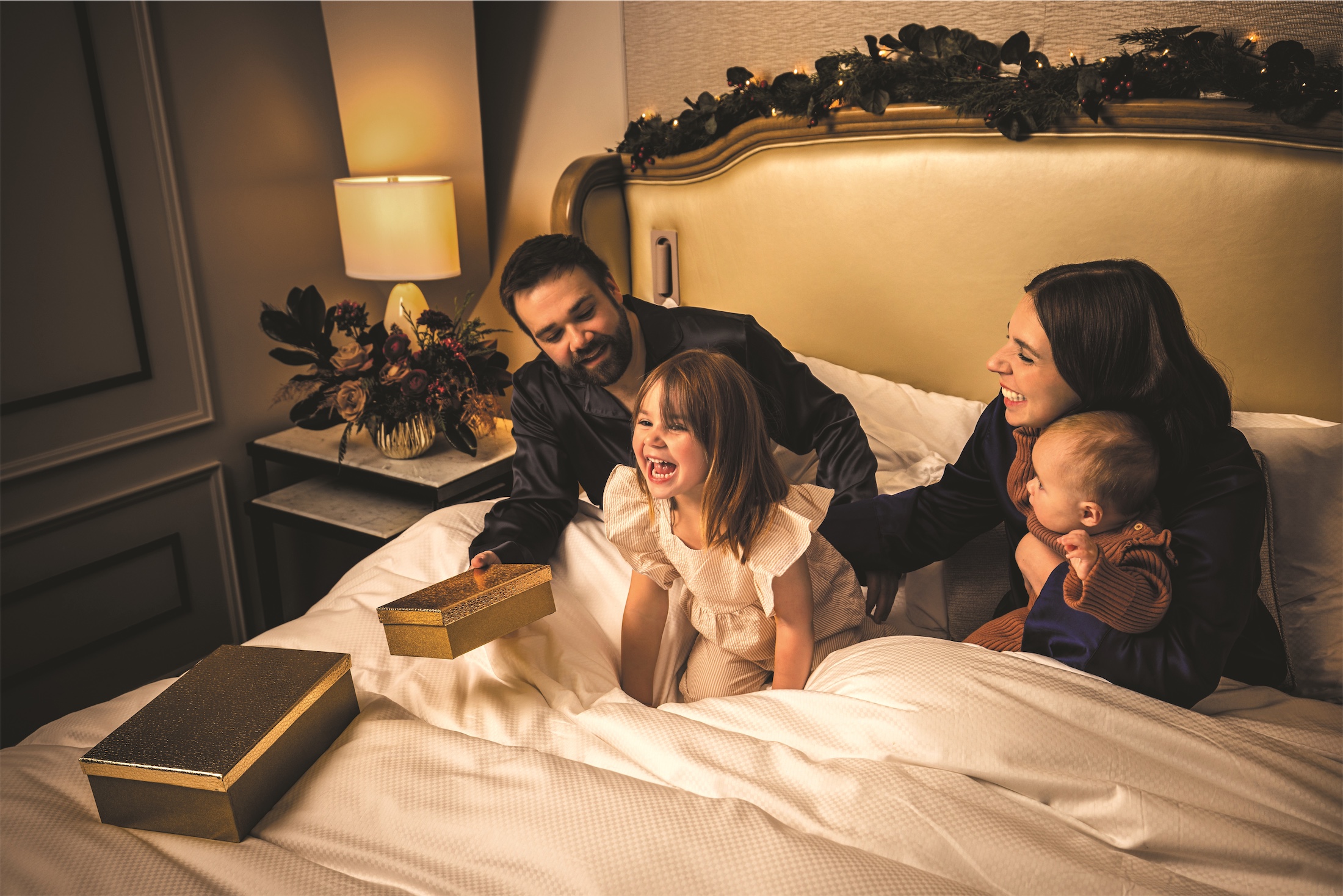 A family on a hotel bed laughing with presents