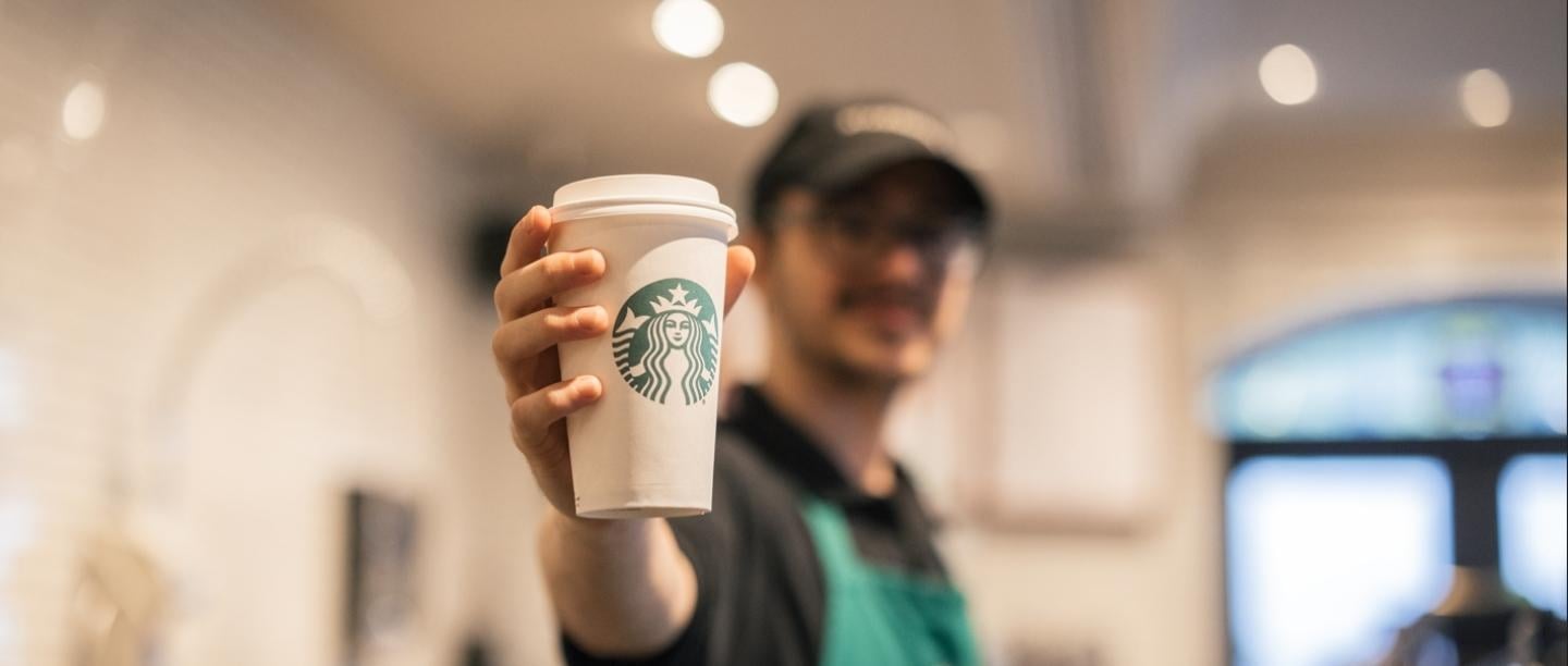 Starbucks employee holding a cup of coffee at Starbucks in Chateau Frontenac
